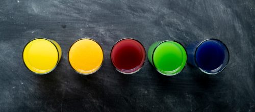 Psihologija boja u brendiranju i digitalnom marketingu - čaše sa raznobojnom tečnošću na tamnoj radnjoj površini